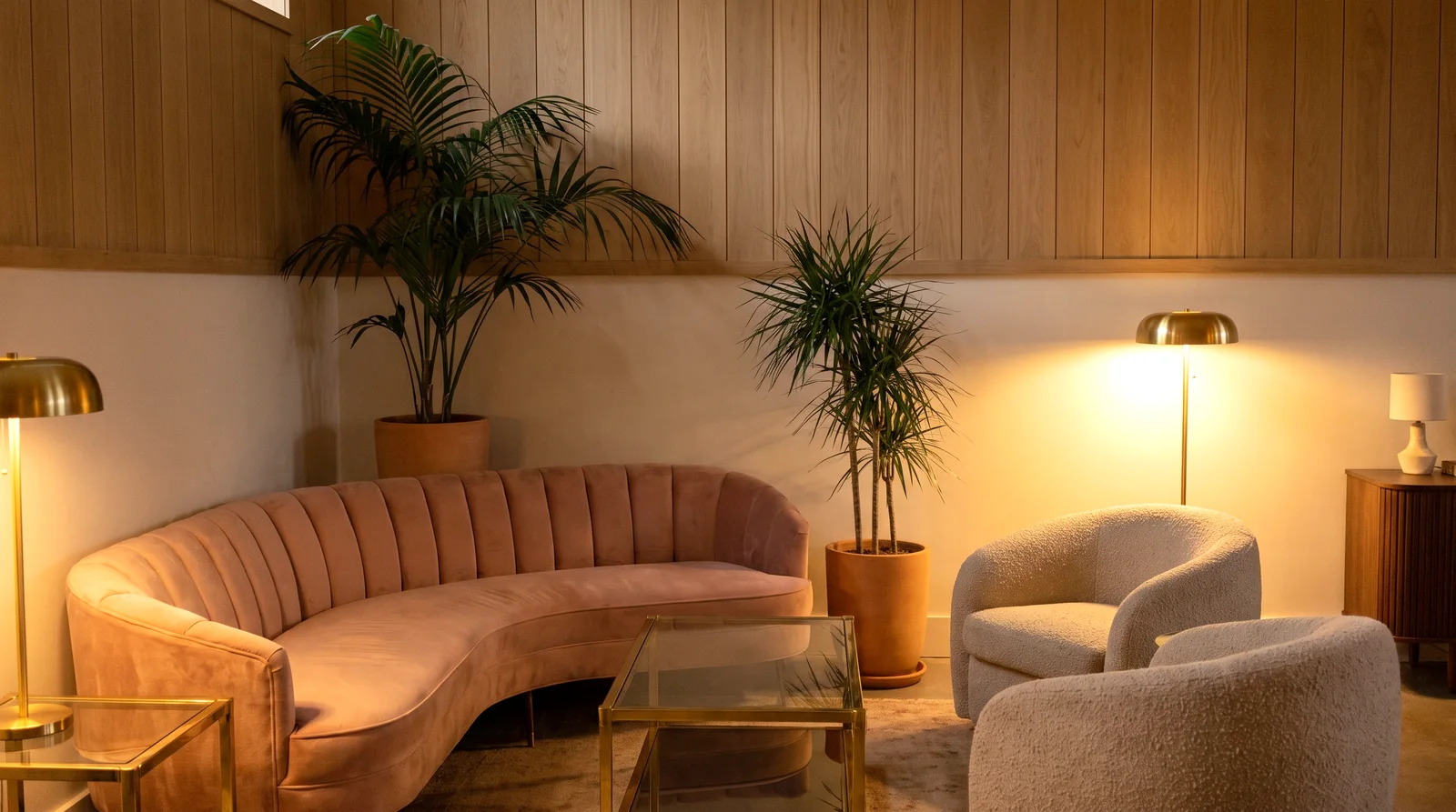 A blush velvet channel-back sofa and boucle armchairs in an oak-paneled hotel lobby